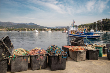 Scenic view of the harbor of the Bay of Fairy Tales with fishing nets on the dock, anchored boats and the coastline in the background in a sunny spring day, Sestri Levante, Liguria, Italy