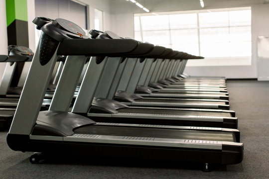 Gym apparatus in a gym hall. Treadmills set in gym interior. Fitness club with equipment.