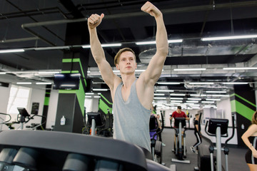 Fototapeta na wymiar Young happy handsome Caucasian man in fitness club. Cardio workout, running on treadmill. Healthy lifestyle, guy training in gym. Flare effect, copy space