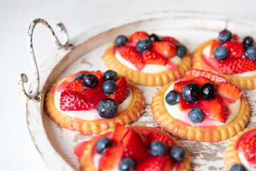 An antique tray with strawberry and blueberry tarts
