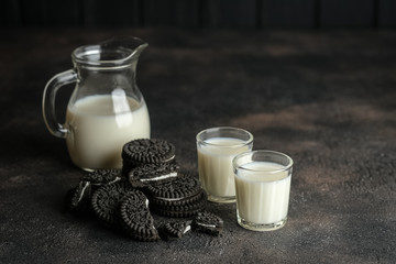 Jug of milk and chocolate chip cookies on a dark background with copy space.