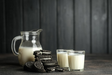 Jug of milk and chocolate chip cookies on a dark background with copy space.