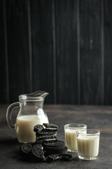 Jug of milk and chocolate chip cookies on a dark background with copy space.