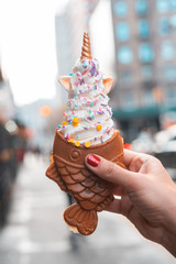 Soft Ice cream with Fish shaped waffle from Korean or Japan. Woman eating a delicious taiyaki outside in New York city. Unicorn decoration. - 266418733