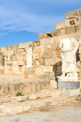 Vertical photography of ancient ruins and statues belonging to the famous Salamis complex in Northern Cyprus taken with blue sky above. The antique landmark is a popular tourist spot.