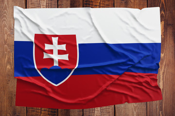 Flag of Slovakia on a wooden table background. Wrinkled Slovak flag top view.