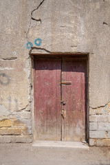 Broken wooden door on grunge stone bricks wall in abandoned Darb El Labana district, Cairo, Egypt