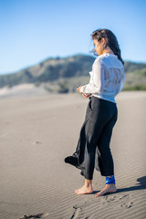 A beautiful young latin girl portrait with straight hair looking at the view. Wearing casual clothes during a beach day in the Pacific Ocean coastline close to Santiago de Chile. An awe wild scenery