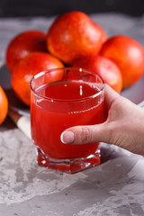 young woman in a gray apron takes a glass of juice blood orange