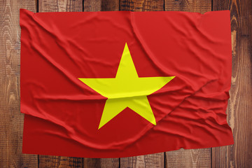 Flag of Vietnam on a wooden table background. Wrinkled Vietnamese flag top view.