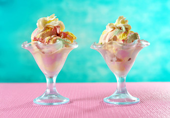 Rainbow ice cream in sundae glasses on bright colorful pink and blue background.