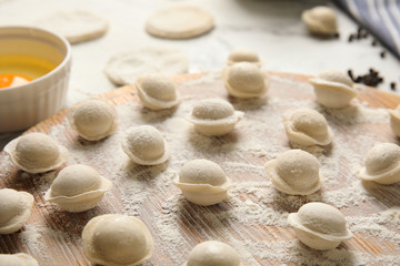 Fototapeta na wymiar Raw dumplings on wooden board, closeup. Process of cooking