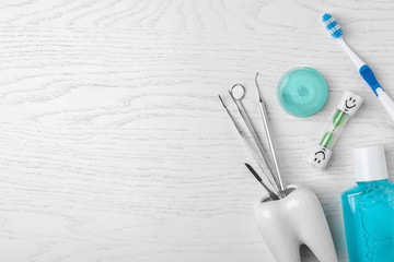 Flat lay composition with dentist tools and teeth care objects on wooden background. Space for text