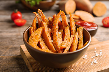 Bowl with sweet potato fries on wooden table