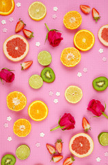 Summertime theme background with fruit, citrus and flowers on pink backdrop.