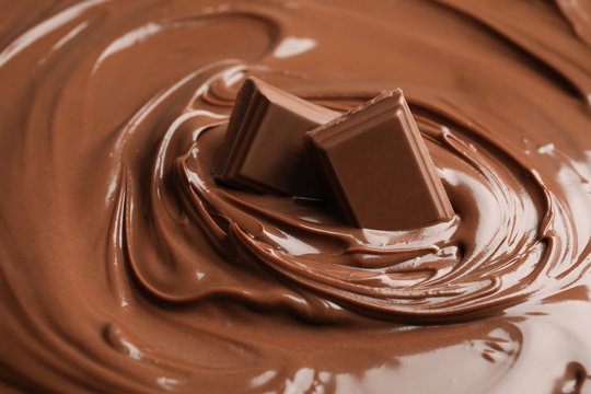 Sweet tasty chocolate cream with pieces as background, closeup