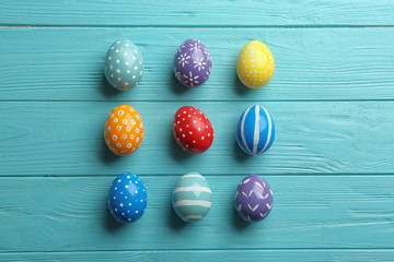 Flat lay composition of painted Easter eggs on wooden table
