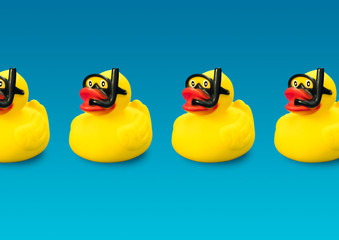 Toy ducks wearing diving goggles and snorkel in blue background