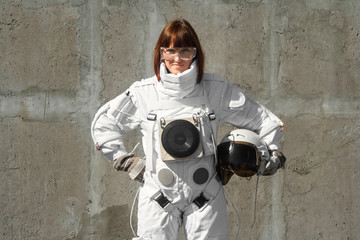 Beautiful girl astronaut without a helmet on the background of a gray wall. Fantastic space suit.