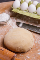 young woman in apron kneading dough on board