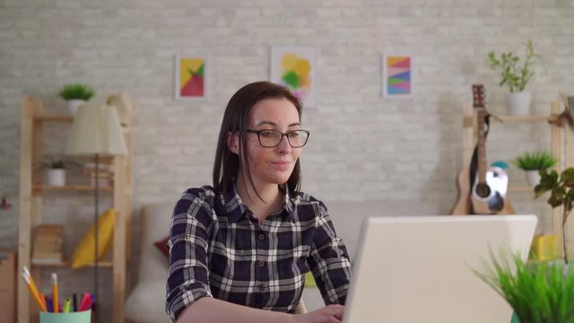 Young woman with a scar from a burn on her face uses a laptop