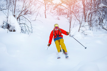 Young man skiing down mountain with ski poles