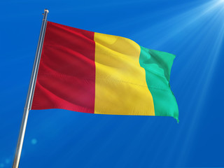 Guinea National Flag Waving on pole against deep blue sky background. High Definition