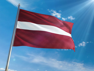 Fototapeta na wymiar Latvia National Flag Waving on pole against sunny blue sky background. High Definition