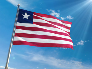 Obraz premium Liberia National Flag Waving on pole against sunny blue sky background. High Definition