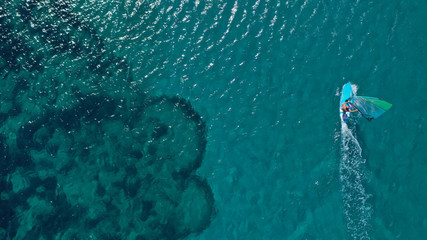 Aerial top view photo of fit man practising wind surfing in exotic open ocean bay with crystal clear emerald sea