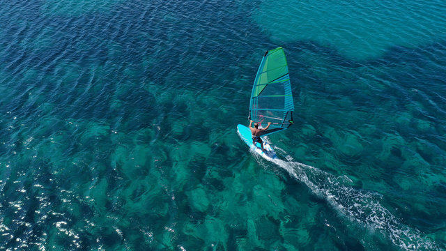 Aerial top view photo of fit man practising wind surfing in exotic open ocean bay with crystal clear emerald sea