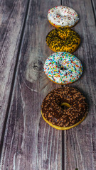 Colorful donuts on the wooden table. Tea time at sweet home.