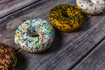 Colorful donuts on the wooden table. Tea time at sweet home.