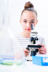 Teen girl student caring out experiments in chemistry class.high school students with microscopes...