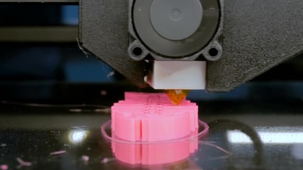 Automatic three dimensional 3D printer machine printing plastic model of pink fish skeleton at modern technology exhibition. 3D printing, additive technologies and 4.0 industrial revolution concept