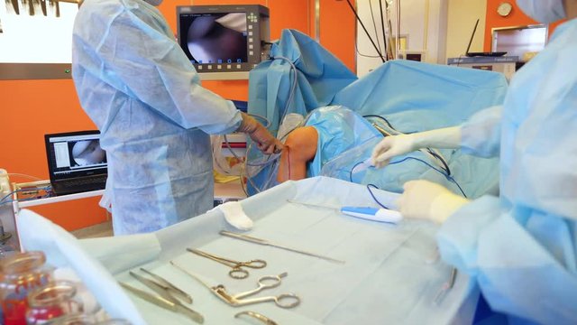 Surgeon and assistant perform a surgery, using modern medical tools.