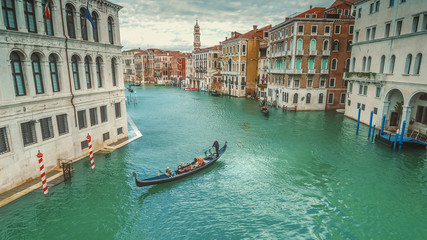 Fototapeta na wymiar Gondola traverses the Grand Canal along amazing city architecture in Venice, Italy