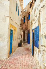 Fototapeta na wymiar Narrow street of the old city with beige and white walls of the residential houses.