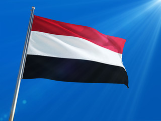Yemen National Flag Waving on pole against deep blue sky background. High Definition