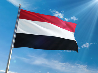 Fototapeta na wymiar Yemen National Flag Waving on pole against sunny blue sky background. High Definition