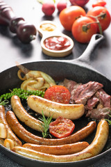 studio shot of grilled sausages with lettuce and tomato ketchup on black background