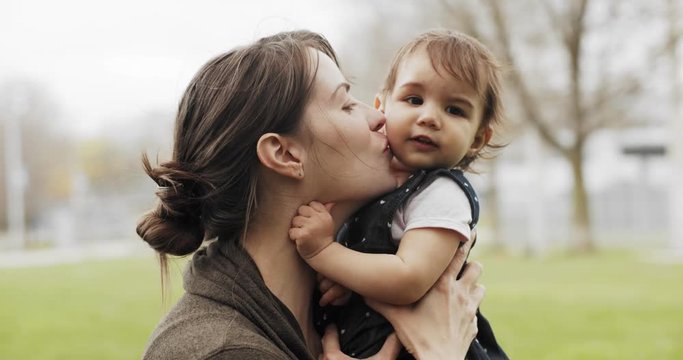 Portrait of a mother kissing her baby girl outdoors