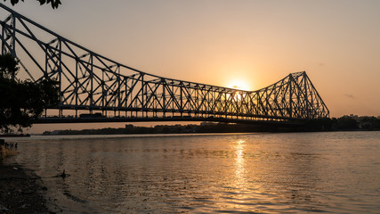 Fototapeta na wymiar Silhouette of Howrah Bridge at the time of Sunrise. Howrah Bridge is a bridge with a suspended span over the Hooghly River in West Bengal.