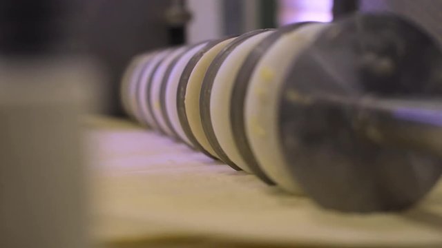 round industrial cutter machine slice large amount of raw dough inside a bread factory