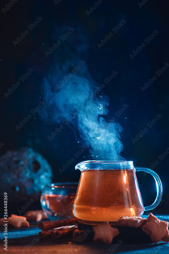Wall mural glass teapot with rising steam and star-shaped cookies on a dark background with copy space. astrono