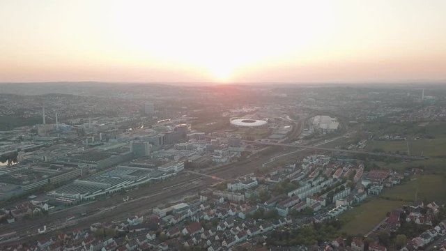 Aerial drone shot of beautiful Stuttgart, Germany while sunset with the Mercedes Benz Arena, the famous Volksfest Wasen and a lot of industry in the foreground and Stuttgart Downtown in the background