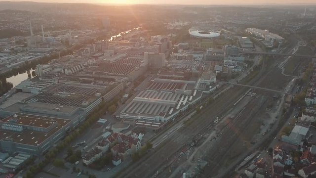 Aerial drone shot of beautiful Stuttgart, Germany while sunset with the Mercedes Benz Arena, the famous Volksfest Wasen and a lot of industry in the foreground and Stuttgart Downtown in the background