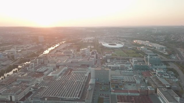 Aerial drone shot of beautiful Stuttgart, Germany while sunset with the Mercedes Benz Arena, the famous Volksfest Wasen and a lot of industry in the foreground and Stuttgart Downtown in the background