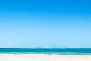 Fototapeta na wymiar Blue sea white beach under bright sky at Yas Island. Abu Dhabi. UAE