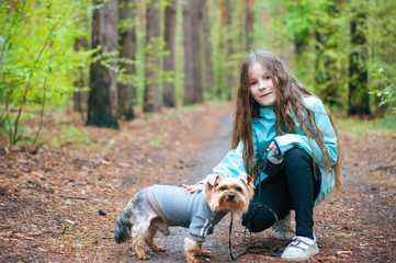 Little girl with dog walking on the road in forest